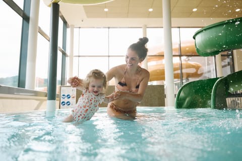 Mama spielt mit ihrem Baby im warmen Babybecken des Hallenbads