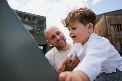 Papa und Sohn lachen gemeinsam auf dem Spielplatz